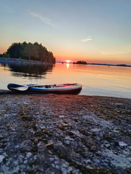 A breathtaking Saimaa sunset with a paddleboard silhouetted against the glowing sky.